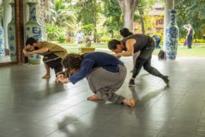 three men practicing qigong tiger exercise crouching 